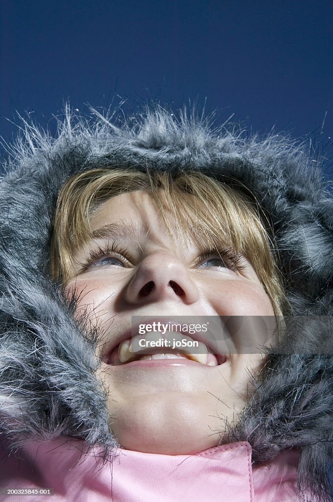 Girl (10-12) wearing hooded coat, looking up smiling, close-up