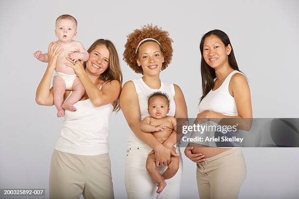 two mothers and baby boys (3-5) months with expectant mother, portrait - beige pants stock-fotos und bilder