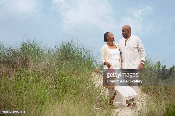 mature couple on beach path - summer cardigan women stockfoto's en -beelden