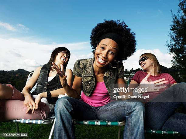 young woman with girlfriends smiling with hands outward, portrait - schouders ophalen stockfoto's en -beelden