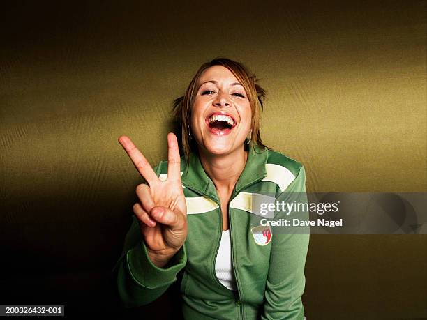 young woman making peace sign, smiling, portrait, close-up - peace sign stock pictures, royalty-free photos & images