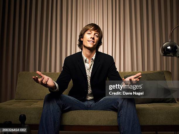 young man sitting on couch with hands outward, portrait - persuasion stock pictures, royalty-free photos & images