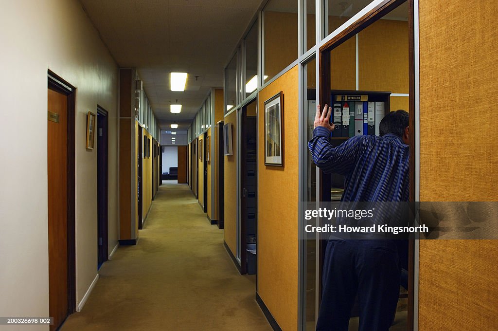 Businessman looking into office by hallway, rear view