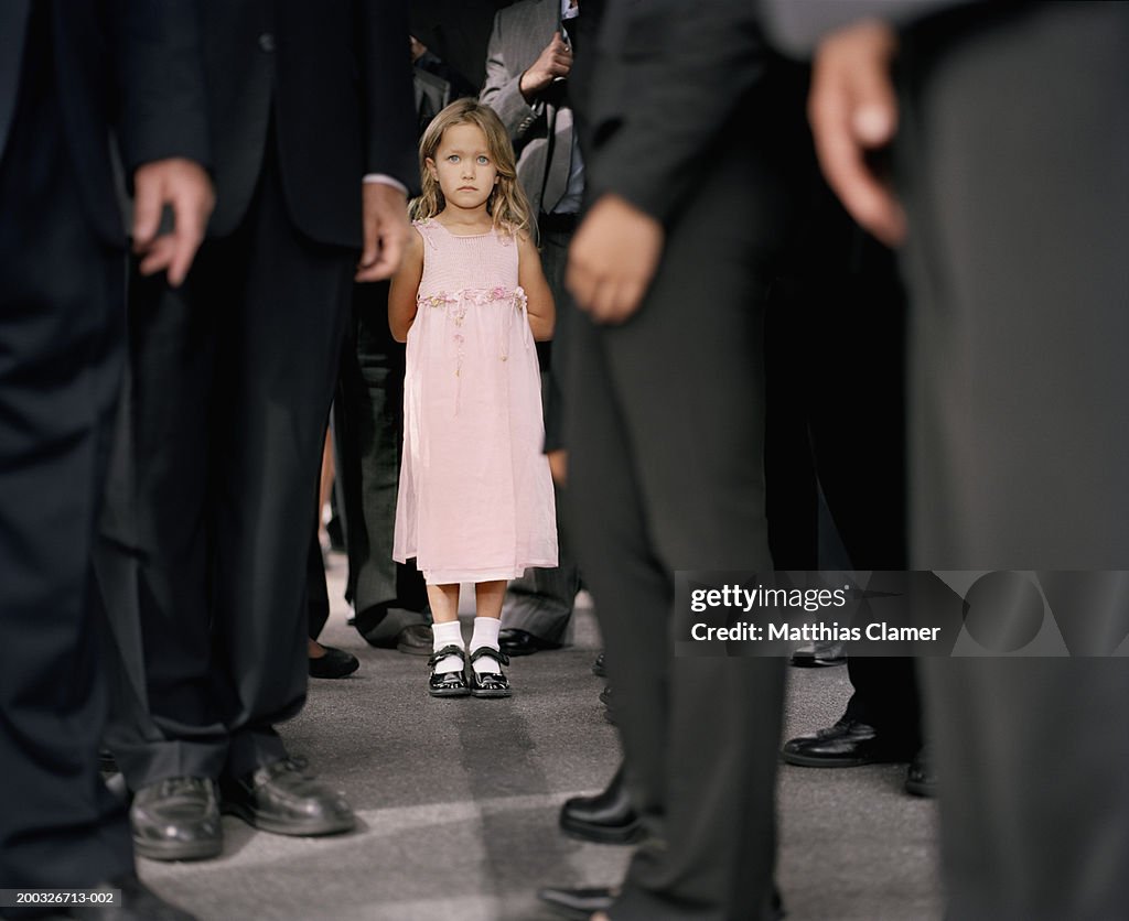 Girl (4-6) standing in crowd of businesspeople (focus on girl)