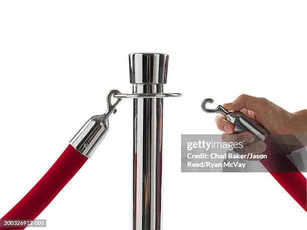 man attaching velvet rope to barrier pole, close-up of hand - roped off stockfoto's en -beelden