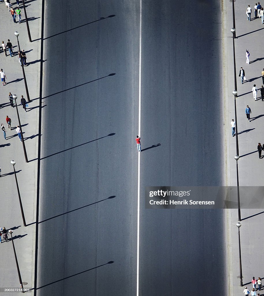 Man standing on white line in middle of road, elevated view