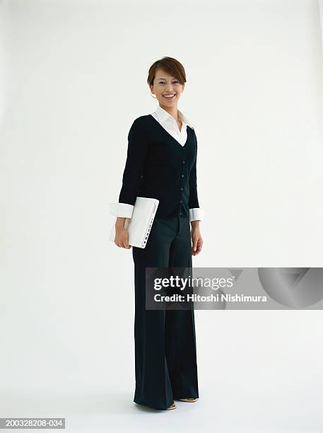 businesswoman holding laptop, smiling - pant suit stockfoto's en -beelden