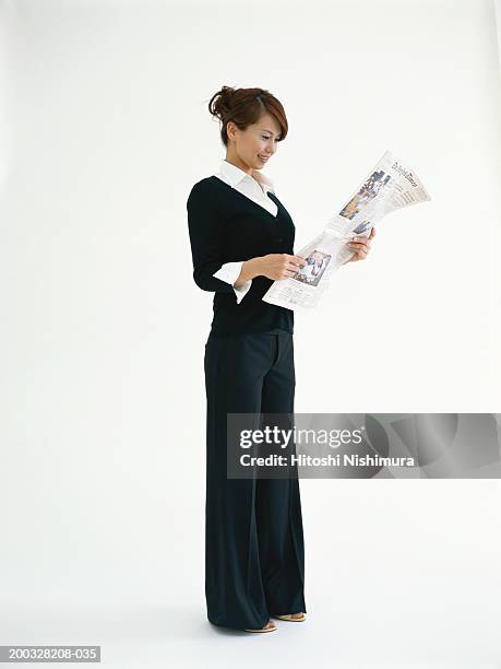 businesswoman reading newspaper, smiling - business women pants stockfoto's en -beelden