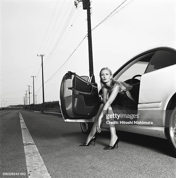 woman sitting in car with door open (b&w) - menselijke voet stockfoto's en -beelden