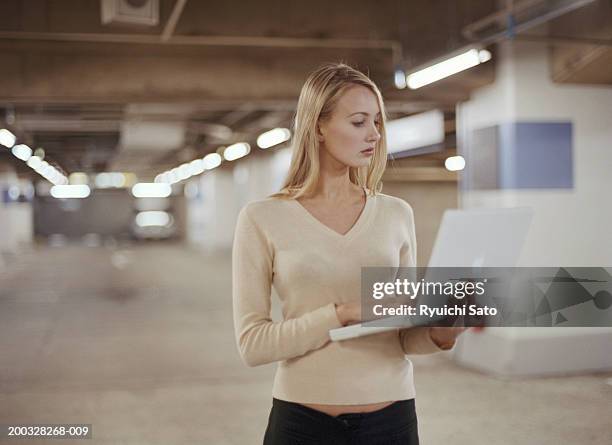 young woman standing at car park, using laptop - keyboard instrument stock pictures, royalty-free photos & images