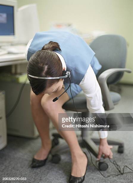 woman on chair wearing headset, looking down - haarschleife stock-fotos und bilder
