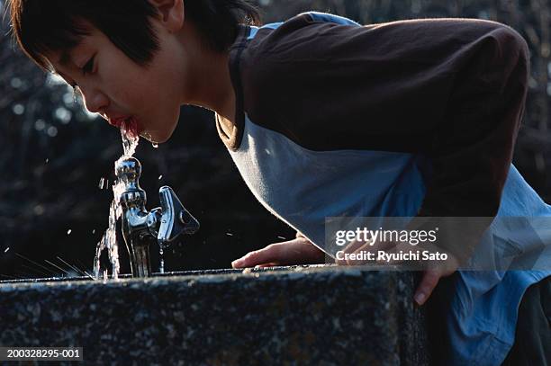 boy (3-5) drinking water from faucet, outdoors - drinkwaterfontein stockfoto's en -beelden