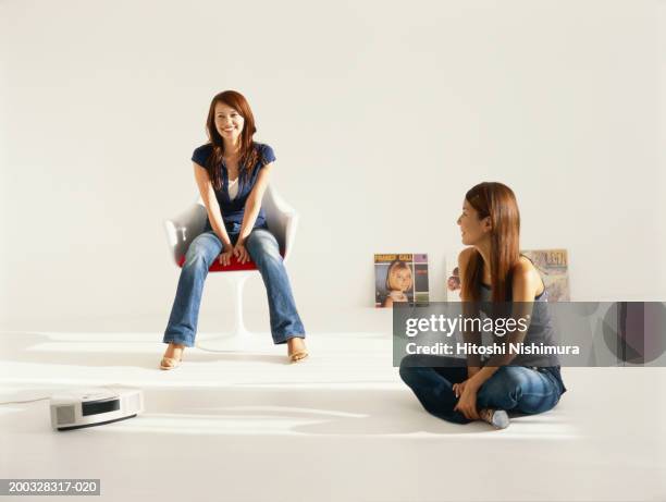 two young women at home smiling - magazine rack stock pictures, royalty-free photos & images