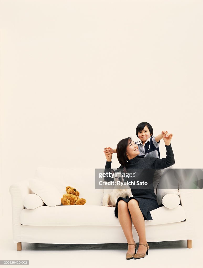 Woman with son (3-4) and puppy on sofa