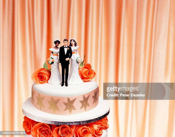 groom and two bride figurines on top of wedding cake, close up - polygamie stockfoto's en -beelden