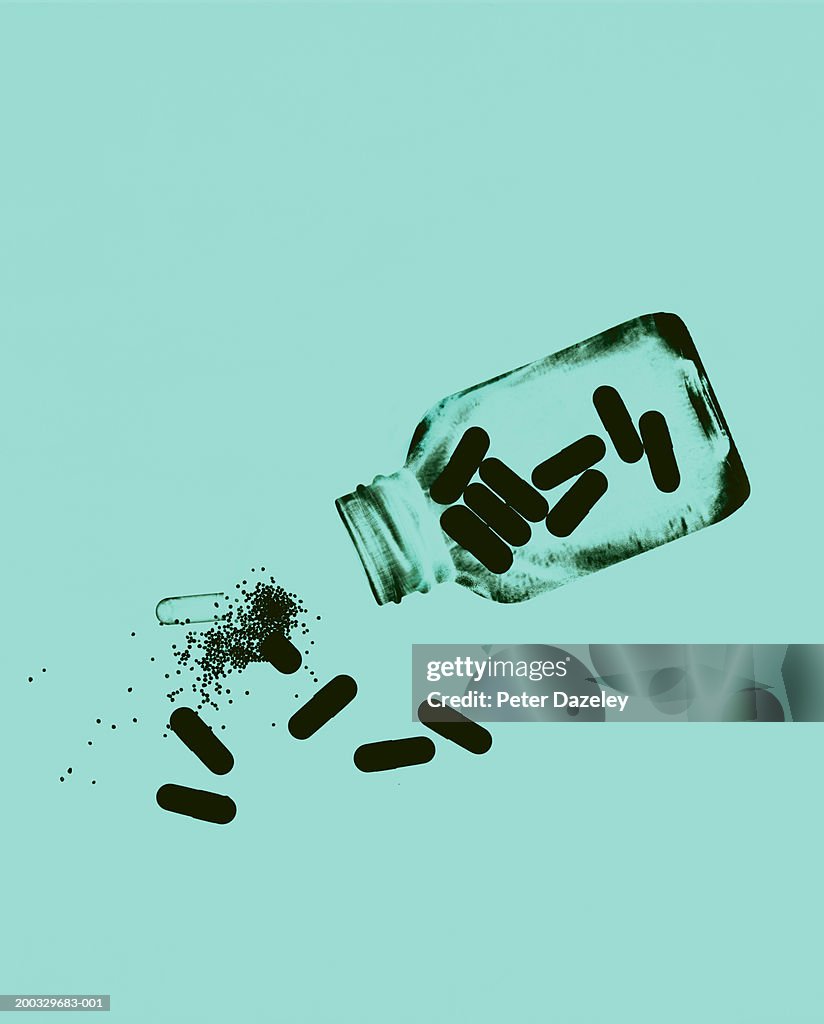 Capsules and pills spilling from bottle, close up (paper negative)