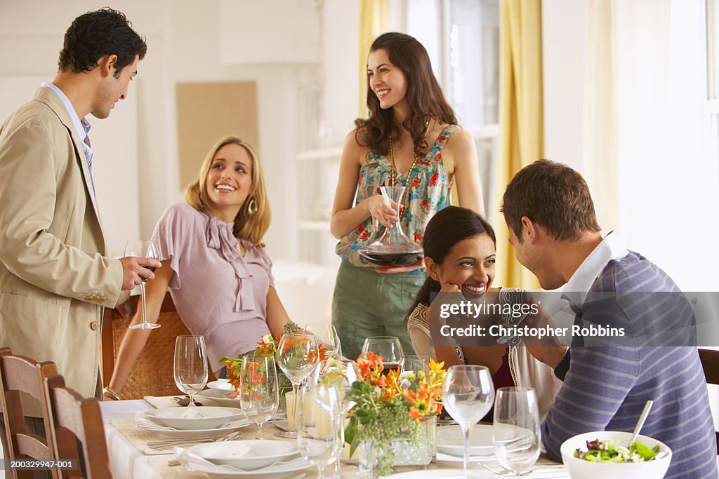 Group of young people gathered around dinner table