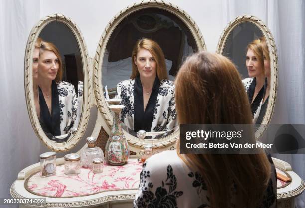 mature woman looking at reflection in bedside mirror - presumir fotografías e imágenes de stock