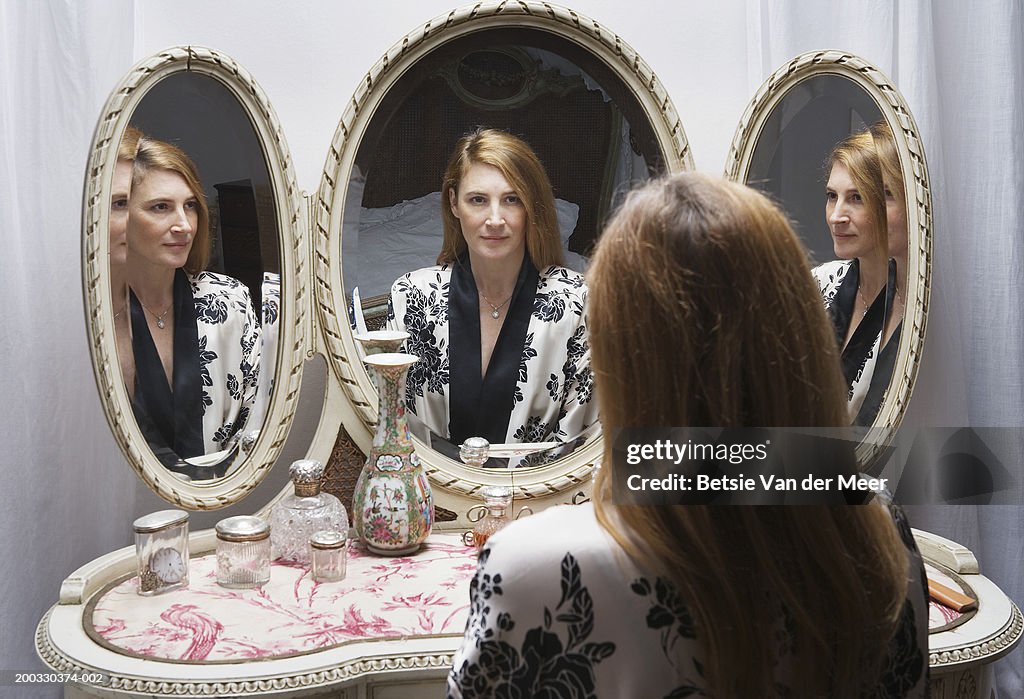 Mature woman looking at reflection in bedside mirror