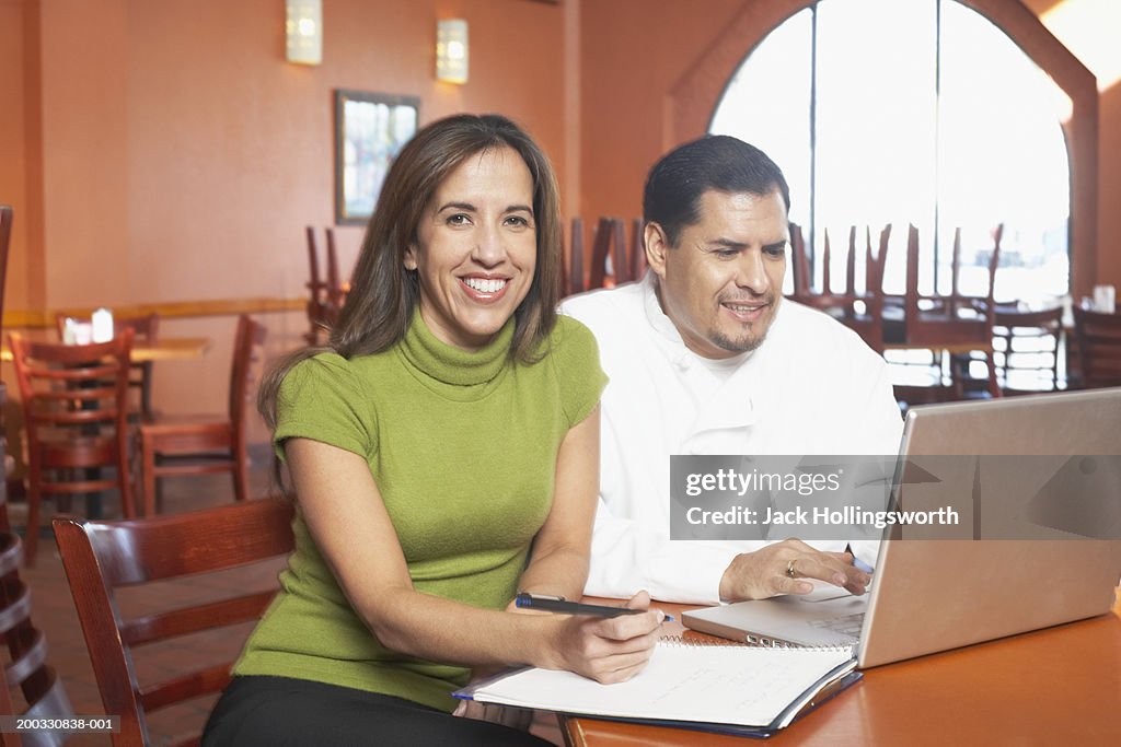 Portrait of a female chef sitting with a male chef