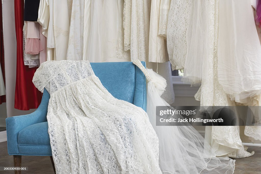 Wedding dress and veil on armchair in clothing store