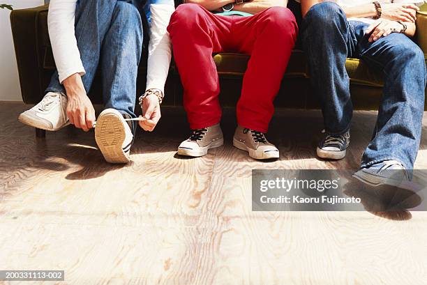 three men sitting on sofa, low section - comfortable shoes stock pictures, royalty-free photos & images