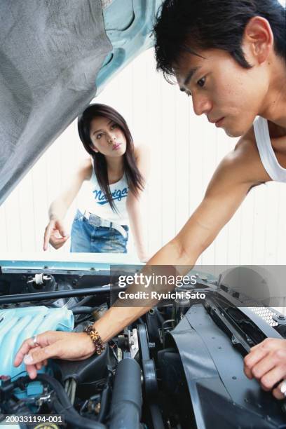 man fixing car while woman pointing out - car engine close up stock pictures, royalty-free photos & images