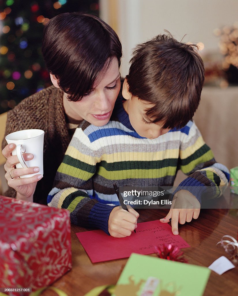 Mother helping son (6-8) write christmas card