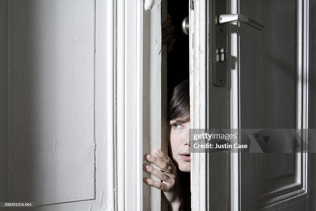 Woman looking through ajar door