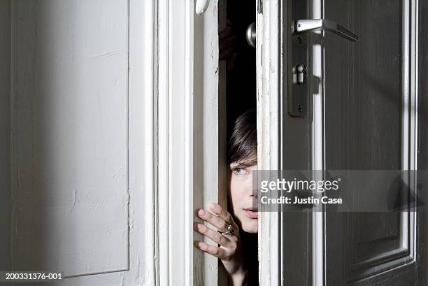 woman looking through ajar door - suspicion stock pictures, royalty-free photos & images