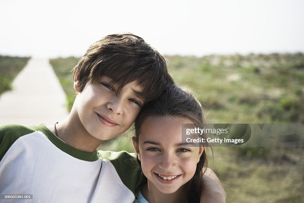 Boy and girl (8-10) on beach boardwalk, close-up, portrait