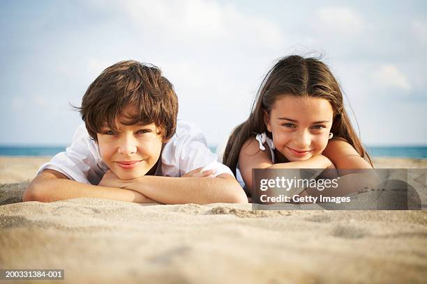 niño y niña (8-10) yacer en playa sonriendo; primer plano; vertical - boy and girl fotografías e imágenes de stock