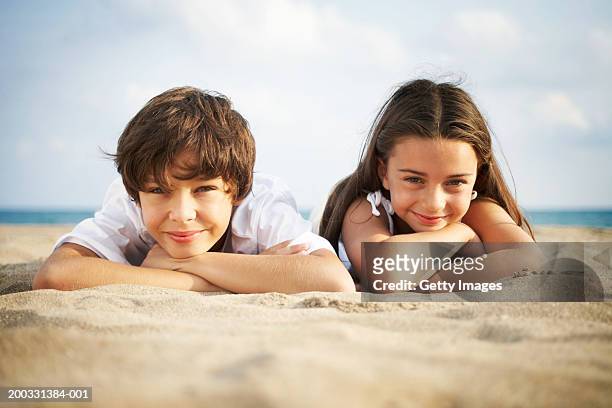 rapaz e rapariga (8- 10) deitado na praia, sorridente, close-up, retrato - happy kids imagens e fotografias de stock