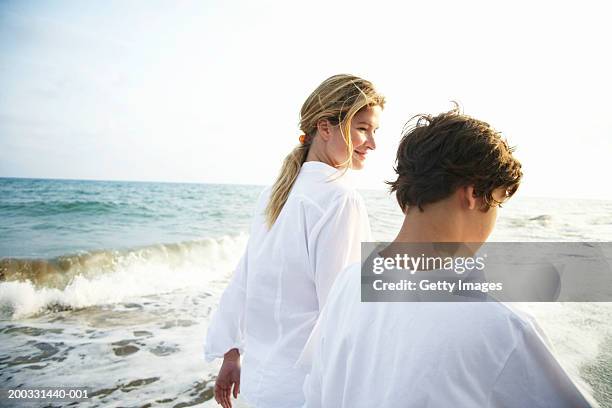 mother and son (8-10) walking on beach, rear view, close-up - blouse back stock pictures, royalty-free photos & images