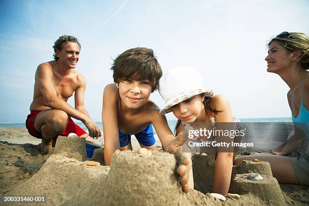 family building sandcastles on beach, boy (8-10) smiling, portrait - red white and blue beach stock pictures, royalty-free photos & images