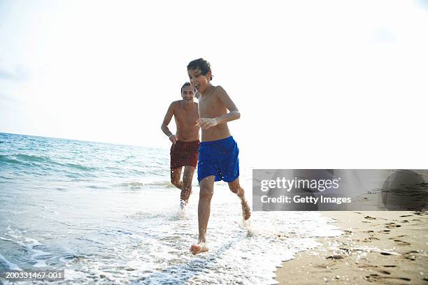 father and son (8-10) running on beach - calções azuis - fotografias e filmes do acervo