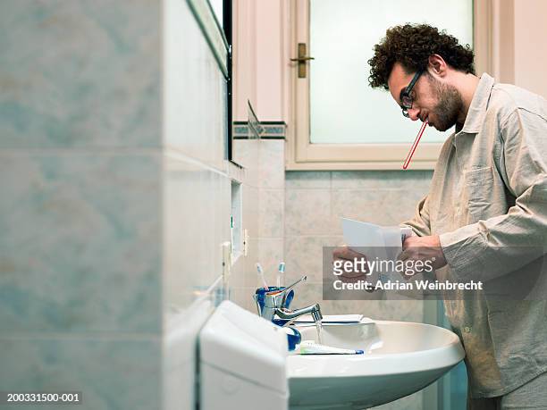 man opening letter in bathroom, toothbrush in mouth, side view - man open mouth stock pictures, royalty-free photos & images