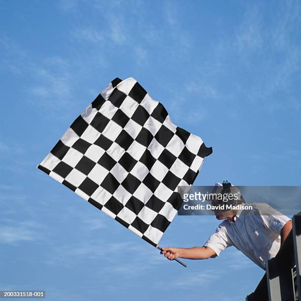 auto race official waving checkered flag, low angle view - checkered flag stock-fotos und bilder