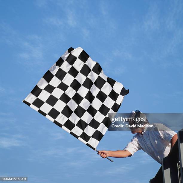 auto race official waving checkered flag, low angle view - drapeau à damiers photos et images de collection