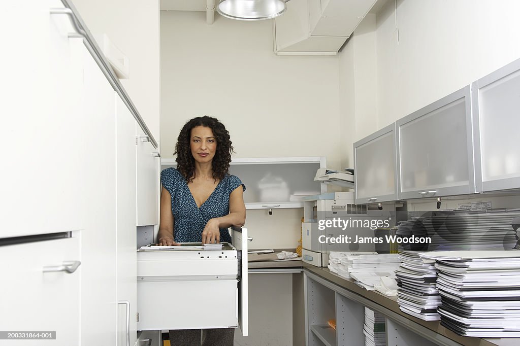 Mature businesswoman by filing cabinet in office, portrait