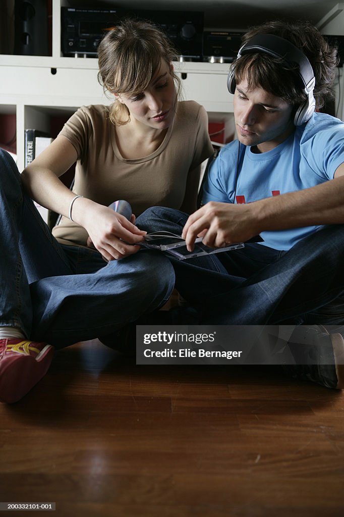 Young couple looking at CD covers, man wearing headphones