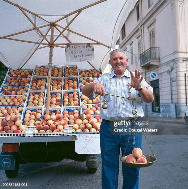 senior man holding scales containing peaches, smiling, portrait - food street market stock pictures, royalty-free photos & images