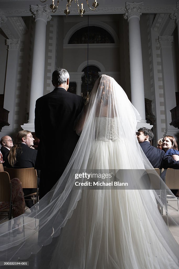 Father walking bride down church aisle, rear view