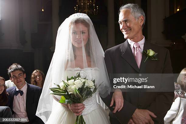 Bride walking down aisle, arm linked with father's, smiling