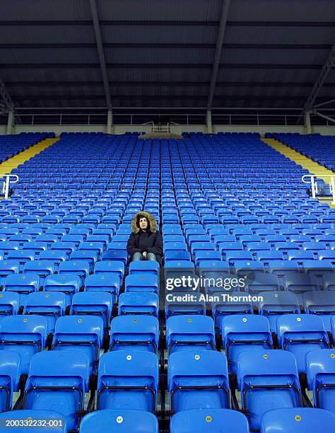 man sitting amongst rows of blue seats in stadium - åskådarläktare bildbanksfoton och bilder