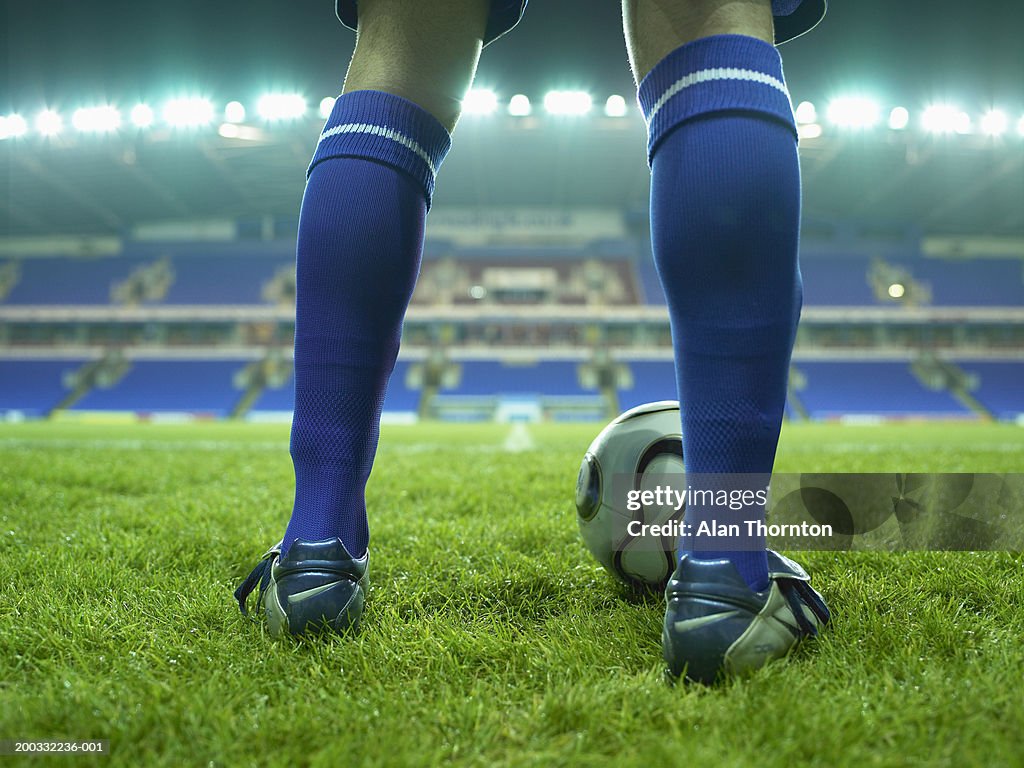 Young male football player on pitch, low section, night