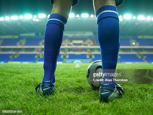 young male football player on pitch, low section, night - pallone da calcio foto e immagini stock