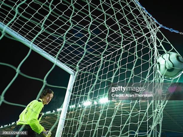 male goalkeeper watching ball bulging in back of net - football player standing stock pictures, royalty-free photos & images