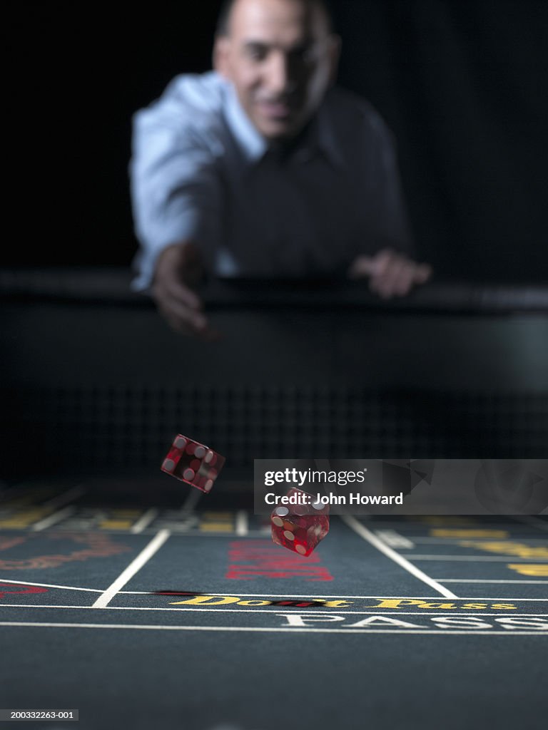 Man rolling dice at craps table (focus on falling dice)