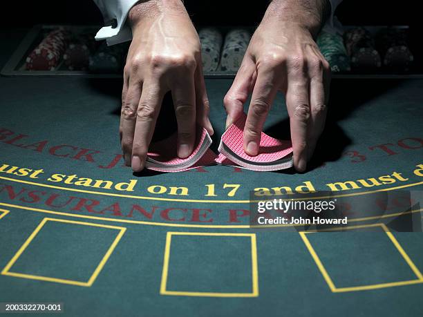 male croupier shuffling cards at table, merging two piles, close-up - casino dealer stockfoto's en -beelden